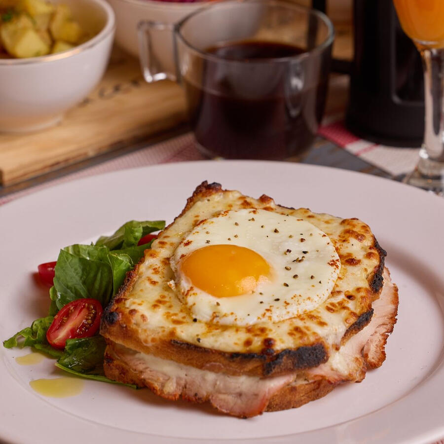 Cambia tu desayuno habitual por un Croque-Madame: pan crujiente, jamón, queso gratinado y huevo frito. ¡Un brunch francés irresistible!